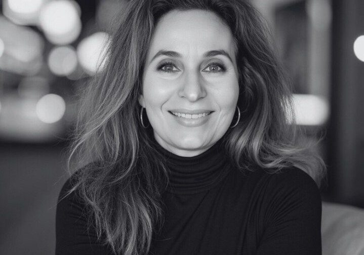 Black and white portrait of a smiling woman with long hair and a turtleneck.
